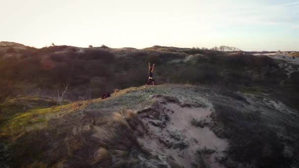 Mujer practicando yoga en las dunas al amanecer. Disparo de dron. Antena.  - Metraje, vídeo