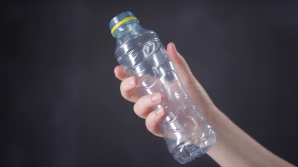 Lähikuva kuvamateriaalia tunnistamaton naisten käsi rypistymässä tyhjä muovi vesipullo taistelevat ympäristön - Materiaali, video