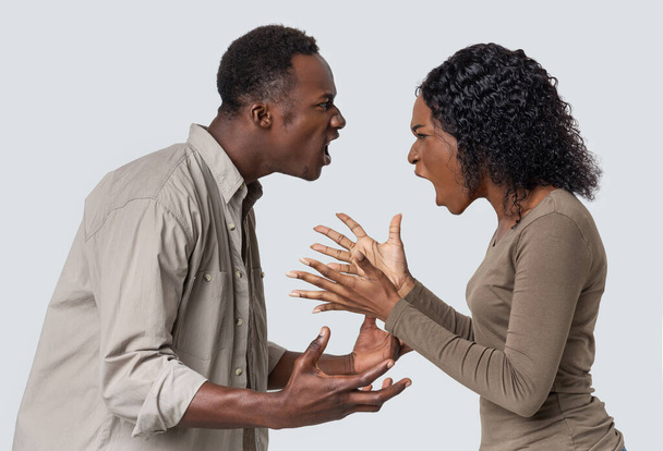 Wütender schwarzer Mann und Frau im Kampf um grauen Hintergrund - Foto, Bild
