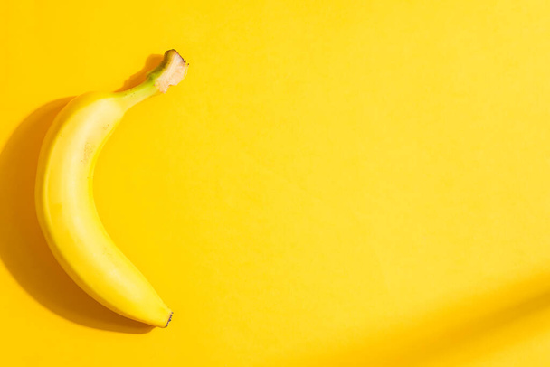 Kreatywna rama owoców z dojrzałego świeżego żółtego banana na tym samym tle koloru z twardymi cieniami, przestrzeń kopiowania. Widok góry. Wegetariańska koncepcja zdrowej żywności. - Zdjęcie, obraz
