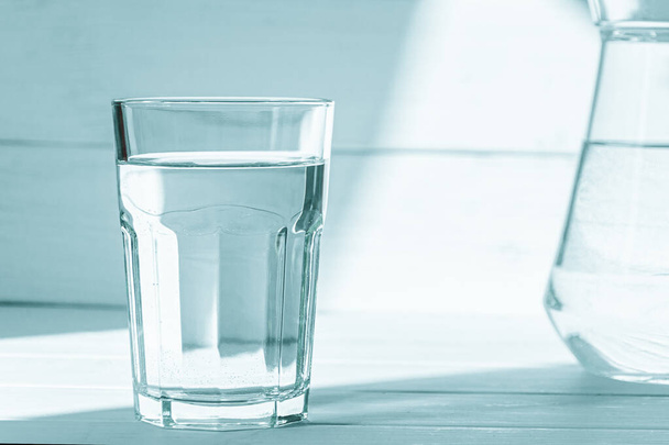 Pure clear water in the glass stands on a wooden background. Ecology. Healthy lifestyle - Photo, Image