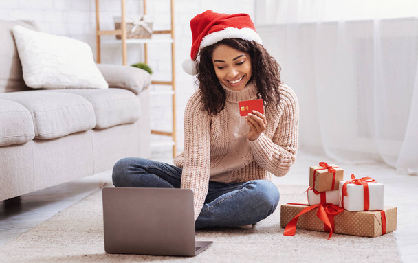 Kerstinkopen. Zwarte dame met laptop met creditcard - Foto, afbeelding