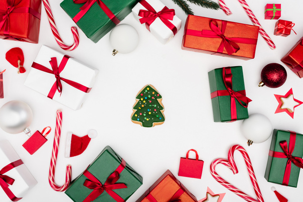 Blick von oben auf Lebkuchen-Weihnachtsbaum umgeben von Geschenkschachteln und Christbaumkugeln auf weißem Hintergrund - Foto, Bild
