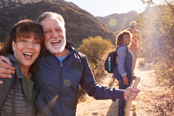 Portrait Of Smiling Senior Friends Hiking In Along Trail Countryside Together - Fotó, kép