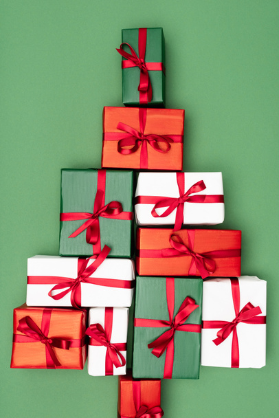 top view of colorful gift boxes in shape of christmas tree on green background - Foto, imagen