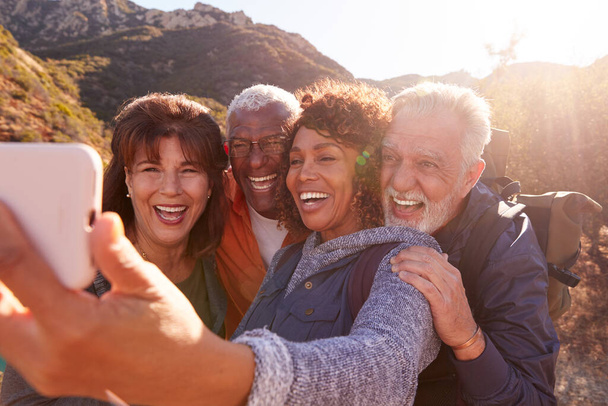 Group Of Senior Friends Posing For Selfie As They Hike Along Trail In Countryside Together - Photo, Image