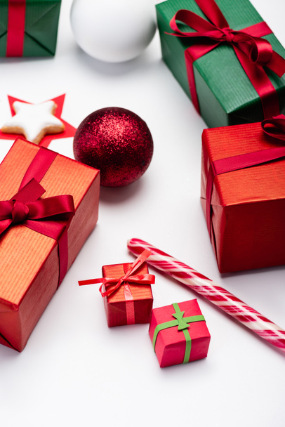 wielobarwne pudełka z prezentami, kulki świąteczne, trzcina cukrowa i ciasteczko w kształcie gwiazdy na białym tle - Zdjęcie, obraz