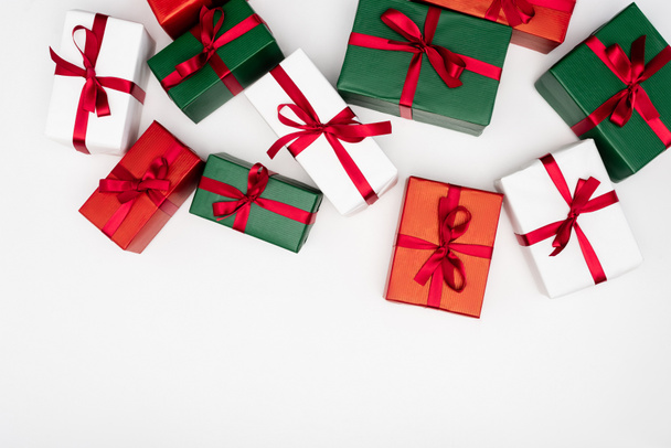 Draufsicht auf bunte Geschenkboxen mit roten Bändern auf weißem Hintergrund - Foto, Bild