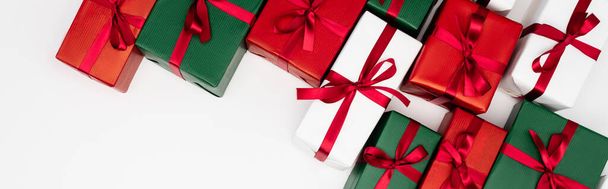 horizontaal concept van kleurrijke geschenkdozen met rode linten op witte achtergrond, bovenaanzicht - Foto, afbeelding