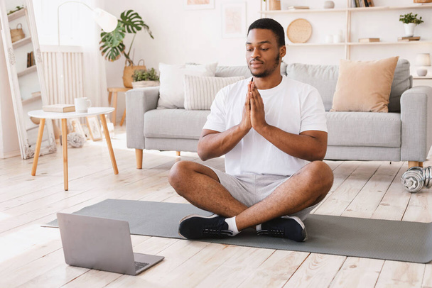 Afrikai-amerikai férfi csinál jóga ül Laptop otthon - Fotó, kép