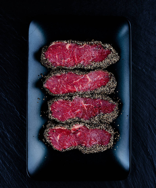 Pepper steaks on black stone plate top view - Photo, image