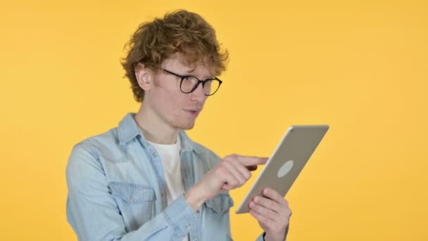 Redhead νεαρός άνδρας γιορτάζει στο Tablet, κίτρινο φόντο  - Πλάνα, βίντεο