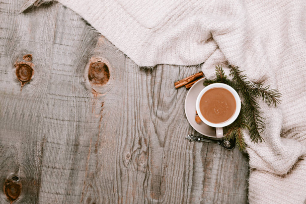 Warme koffiekop verpakt in een gezellige deken op een houten tafel - Foto, afbeelding