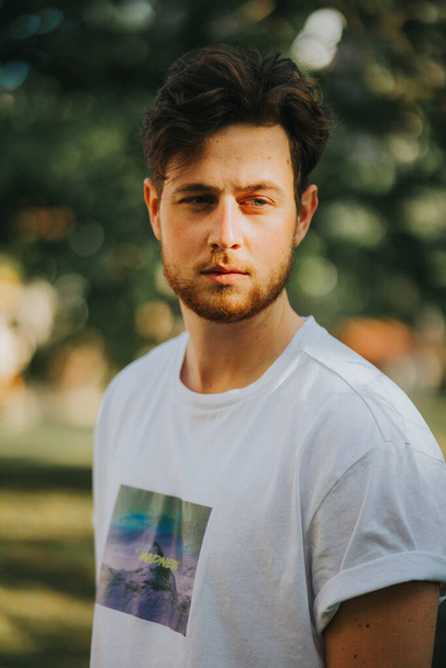 A portrait of a young Caucasian male in a white shirt posing outside - Photo, image