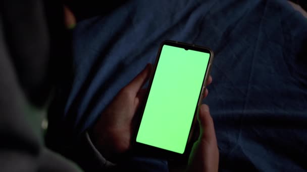 Κουκούλα γυναίκα στο σκοτάδι κατέχει και εξετάζει Smartphone με πράσινη οθόνη αφής. - Πλάνα, βίντεο
