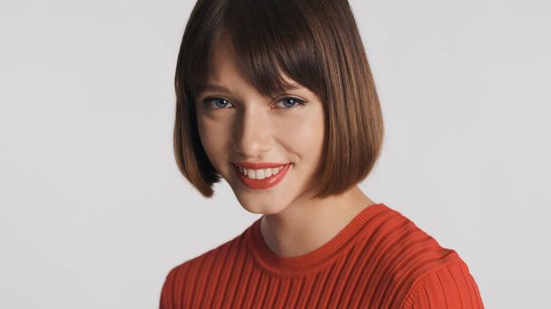Pretty brunette girl with bob hair and red lips look charming over white background. Cute expression - 写真・画像
