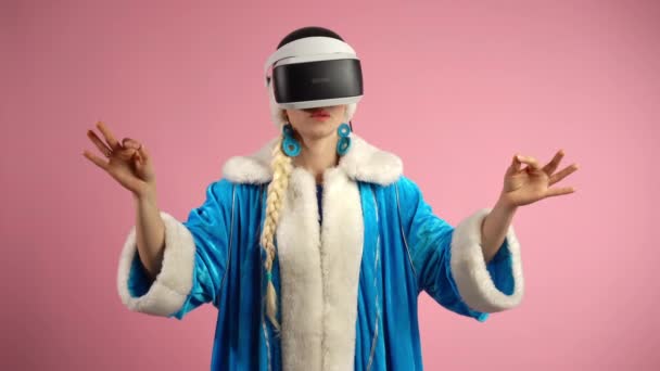 Mujer concentrada que usa auriculares de realidad virtual aumentada en interiores sobre un fondo rosa aislado, mujer que utiliza la innovación tecnológica para jugar videojuegos 3D, imaginación futurista. Concepto de - Metraje, vídeo