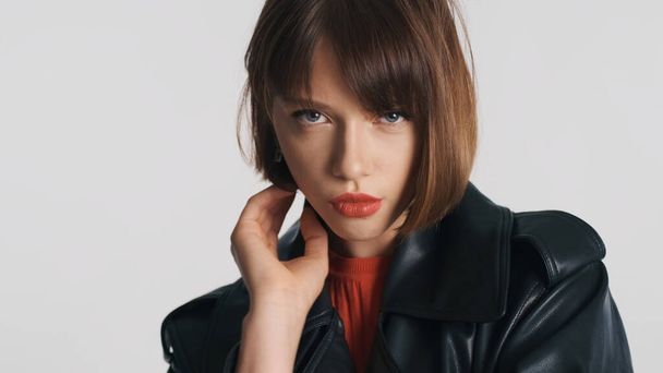 Chica morena de moda con el pelo bob y labios rojos mirando serio sobre fondo blanco. Modelo profesional posando en estudio - Foto, imagen