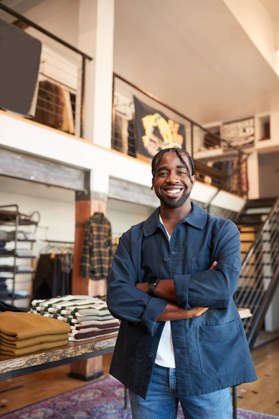 Portrait Of Smiling Male Owner Of Fashion Store Standing In Front Of Clothing Display - Foto, Bild