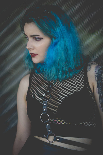 A vertical shot of a stylish blue-haired young woman with mesh blouse - street fashion concept - Zdjęcie, obraz