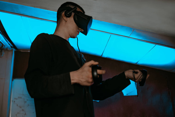 Un uomo a casa con gli occhiali della realtà virtuale. Tiene in mano i controllori. Guy gioca vr giochi - Foto, immagini