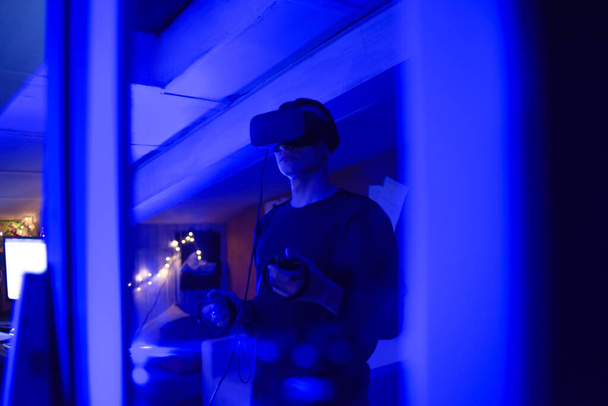Un uomo a casa con gli occhiali della realtà virtuale. Tiene in mano i controllori. Guy gioca vr giochi - Foto, immagini