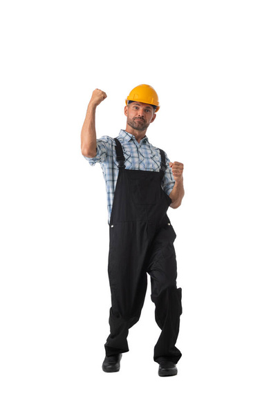 Mature contractor worker in coveralls and hardhat holding fists isolated on white background full length studio portrait - Foto, Imagen