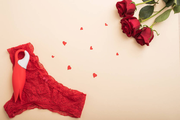 Flat lay. Womens red lace panties clitoral vibrator in the shape of a tulip and scarlet roses. The best gift for a woman for any occasion - Fotografie, Obrázek