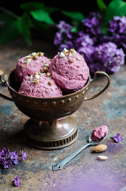 Homemade berry sorbet ice cream with nuts. Bouquet of lilacs on the table. - Foto, afbeelding