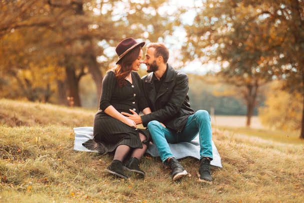Μια φωτογραφία ενός νεαρού ωραίου ζευγαριού την φθινοπωρινή σεζόν στο πάρκο να περνάει μια χαριτωμένη στιγμή - Φωτογραφία, εικόνα