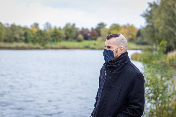 Muž v masce stojí v parku u jezera - Fotografie, Obrázek