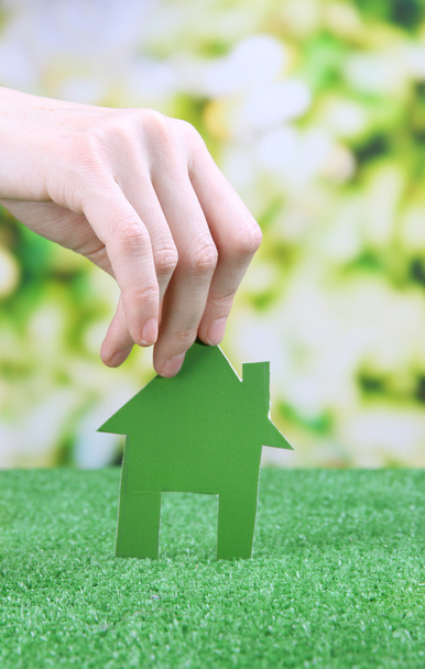 Petite maison en papier à la main sur herbe verte sur fond lumineux
 - Photo, image