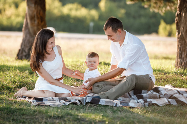 happy family mom dad and baby son happy in nature spending time together on summer sunny day. The concept of a fun holiday outdoors. Happy childhood - Фото, зображення