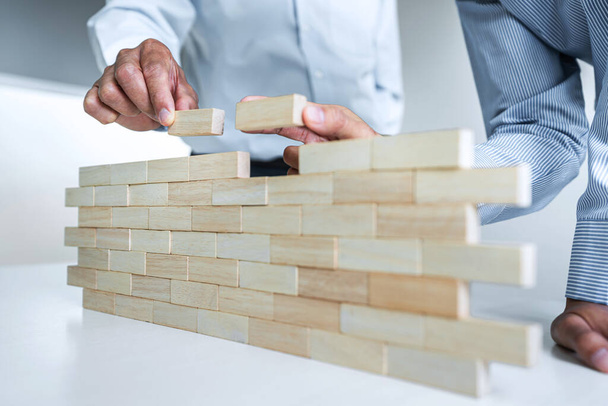 Plan and strategy in business, Risk To Make Business Growth Concept With Wooden Blocks, hand of man has piling up and stacking a wooden block. - Fotografie, Obrázek