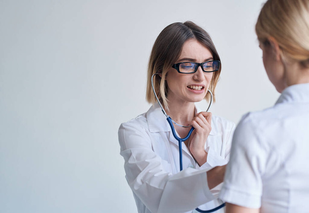 profesionální žena lékař v lékařských šatech a brýle modrý stetoskop pacient - Fotografie, Obrázek