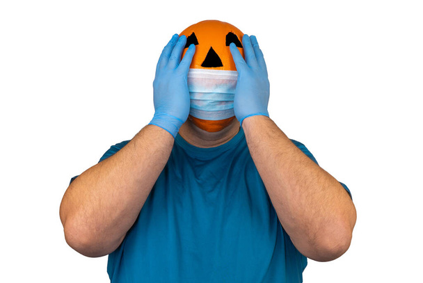 Halloweenpompoen in een medisch ademhalingsverband. Chirurgisch beschermend masker. persoon met oranje duivels masker.  - Foto, afbeelding