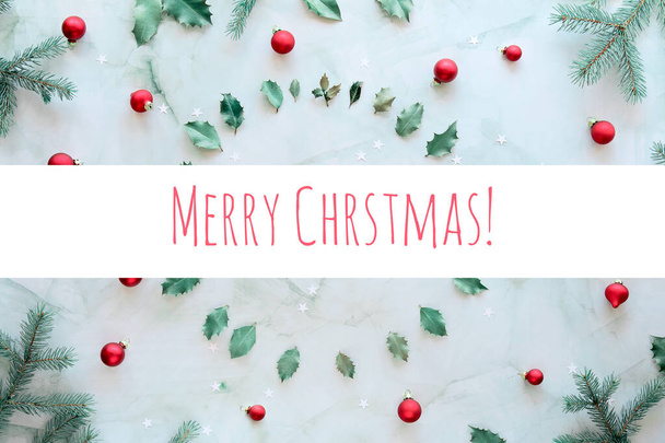 Text Merry Christmas. Marble stone background. Xmas background with natural fir twigs, holly leaves and glass trinkets. Christmas flat lay in green and red. - Foto, imagen