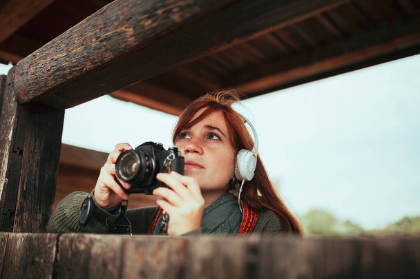 Mujer joven tomando fotos de cabaña de madera en el bosque - Foto, Imagen