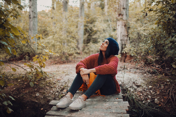 Nuori nainen istuu pienellä puisella sillalla metsässä - Valokuva, kuva