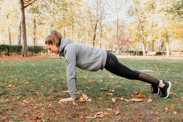 Donna che si allena all'aperto nel parco facendo flessioni - Foto, immagini
