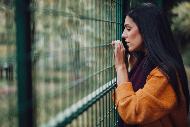 Γυναίκα κοιτάζοντας μέσα από το μεταλλικό φράχτη στο δάσος - Φωτογραφία, εικόνα