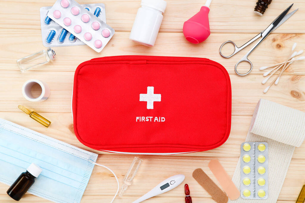 First aid kit with medical supplies on brown wooden table - Fotoğraf, Görsel