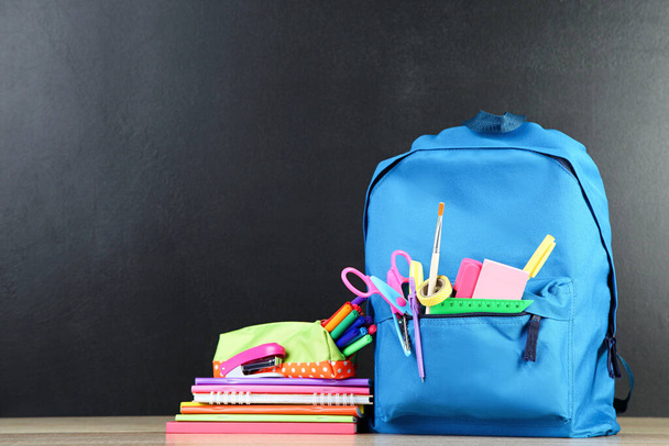 Backpack with school supplies on black background - Photo, Image