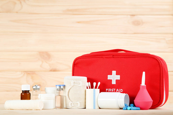First aid kit with medical supplies on brown wooden table - Foto, Imagem