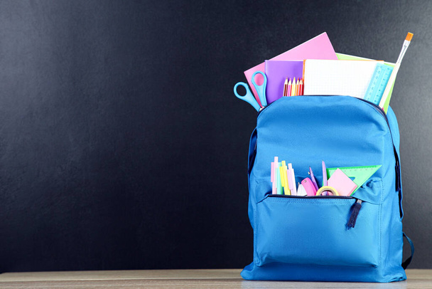 Backpack with school supplies on black background - Фото, изображение