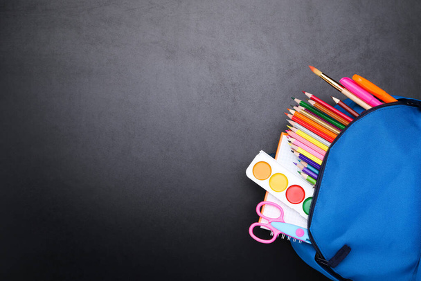 Backpack with school supplies on black background - Φωτογραφία, εικόνα