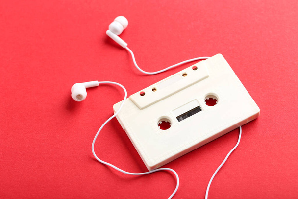 Earphones and cassette tape on red background - Valokuva, kuva