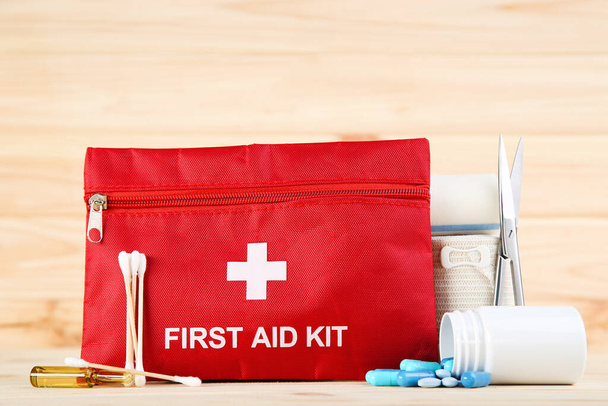 First aid kit with medical supplies on brown wooden table - Fotografie, Obrázek