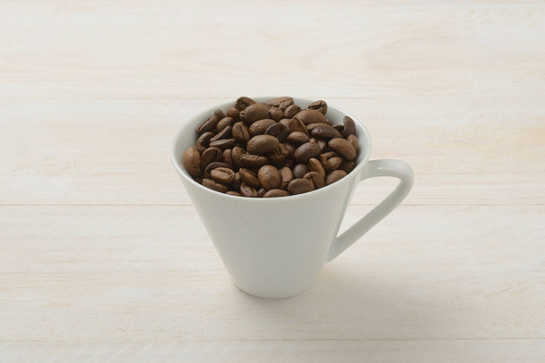 Coffee beans in a cup on white wooden table - Foto, immagini