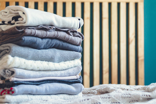A stack of cozy warm winter clothes lies on the bed. - Photo, Image